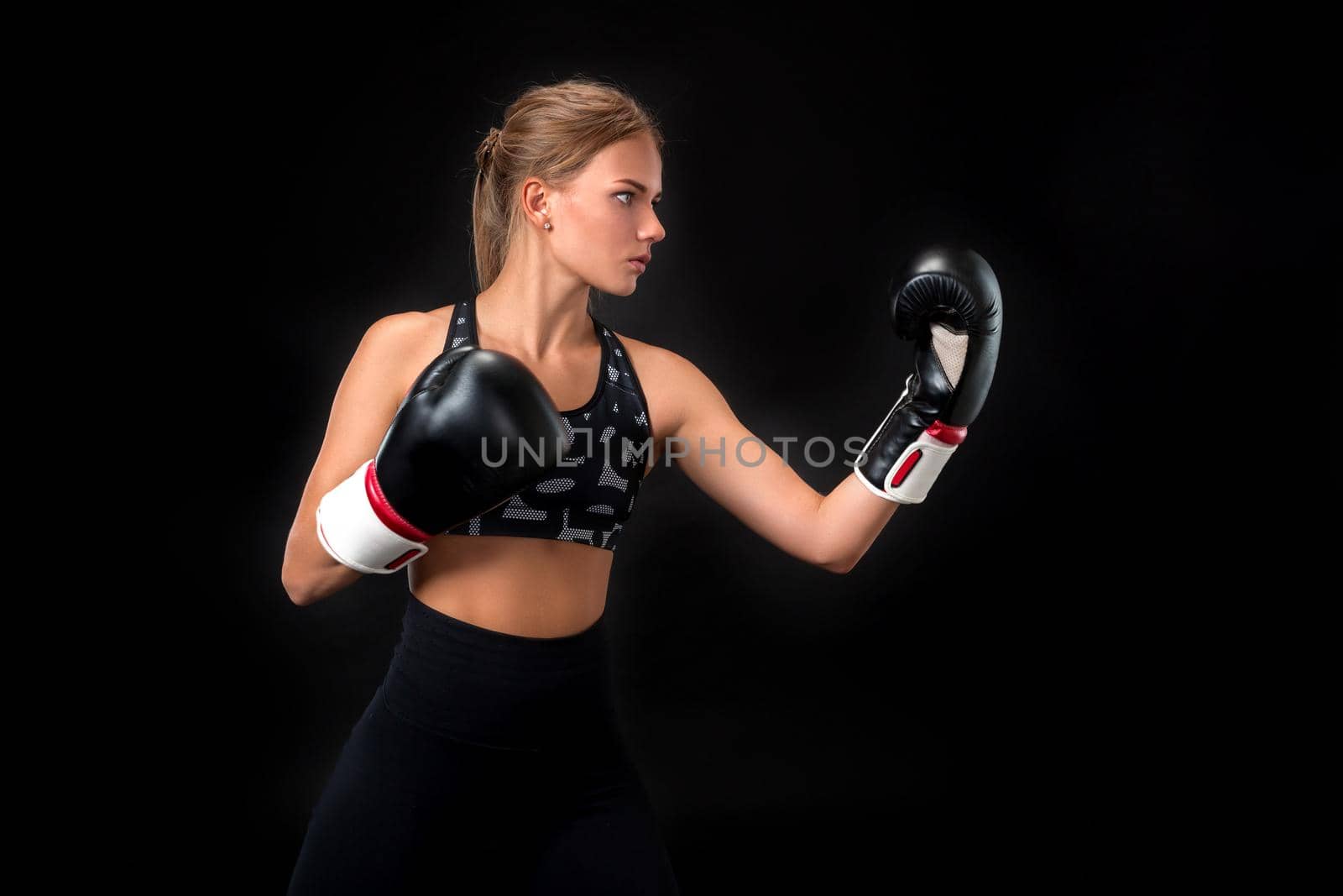 Beautiful female athlete in boxing gloves, in the studio on a black background. by nazarovsergey