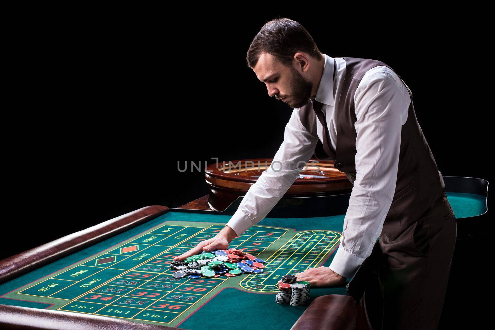 Croupier behind gambling table in a casino on a black background. Gambling. Casino. Roulette. Poker