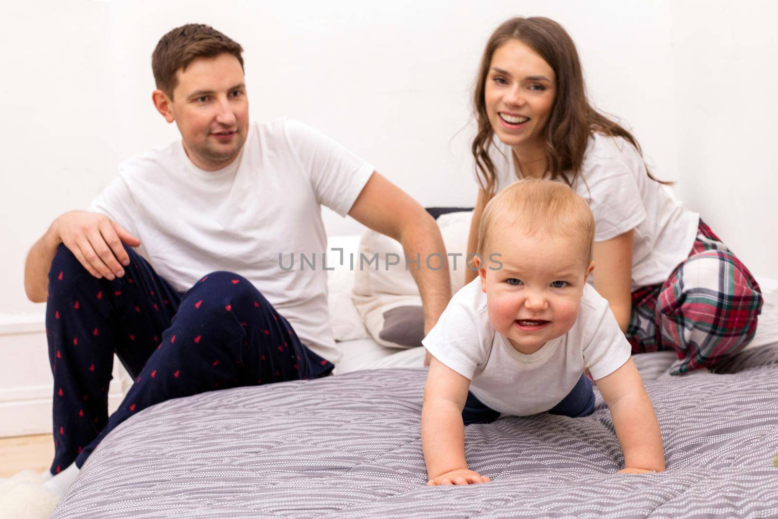 Happy family with funny toddler in bedroom by Demkat