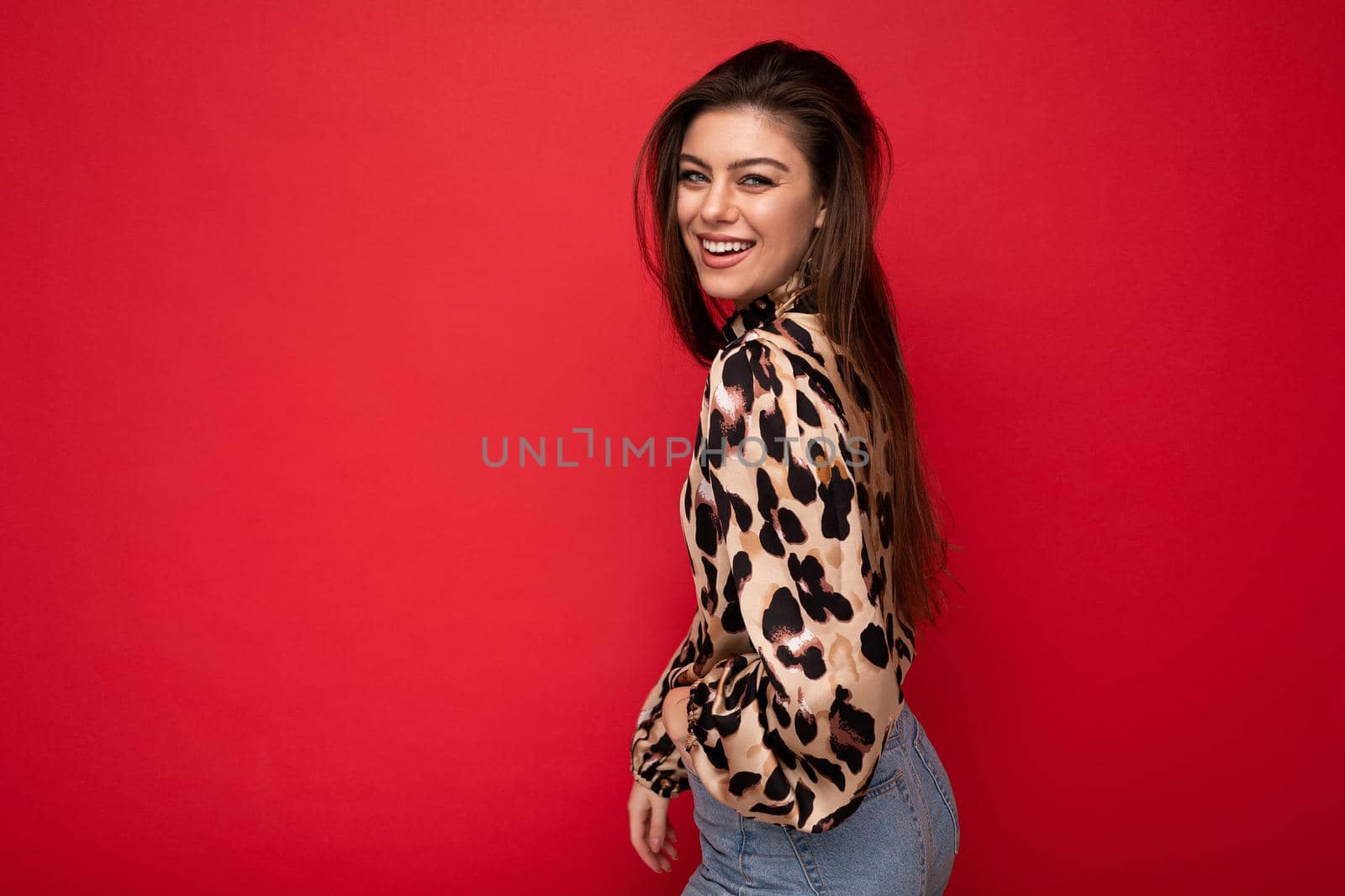 Photo of young positive smiling beautiful fashionable sexy brunette woman wearing stylish leopard blouse isolated on red background with empty space.