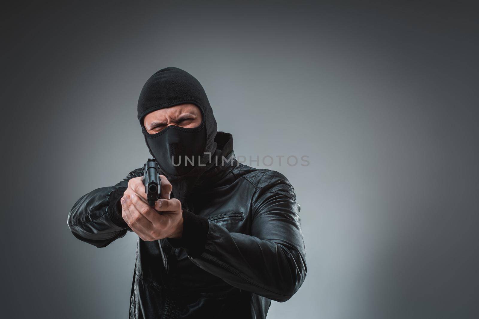 Robber in a mask with a gun, studio shot