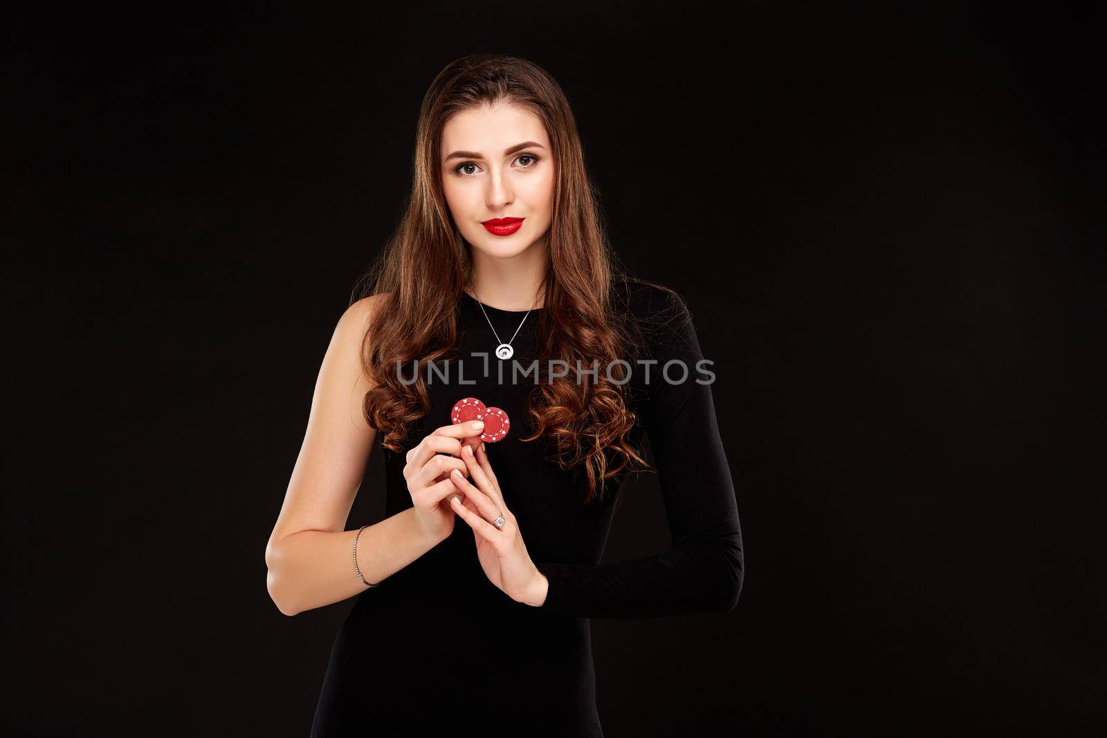 Sexy curly hair brunette posing with chips in her hands, poker concept black background by nazarovsergey