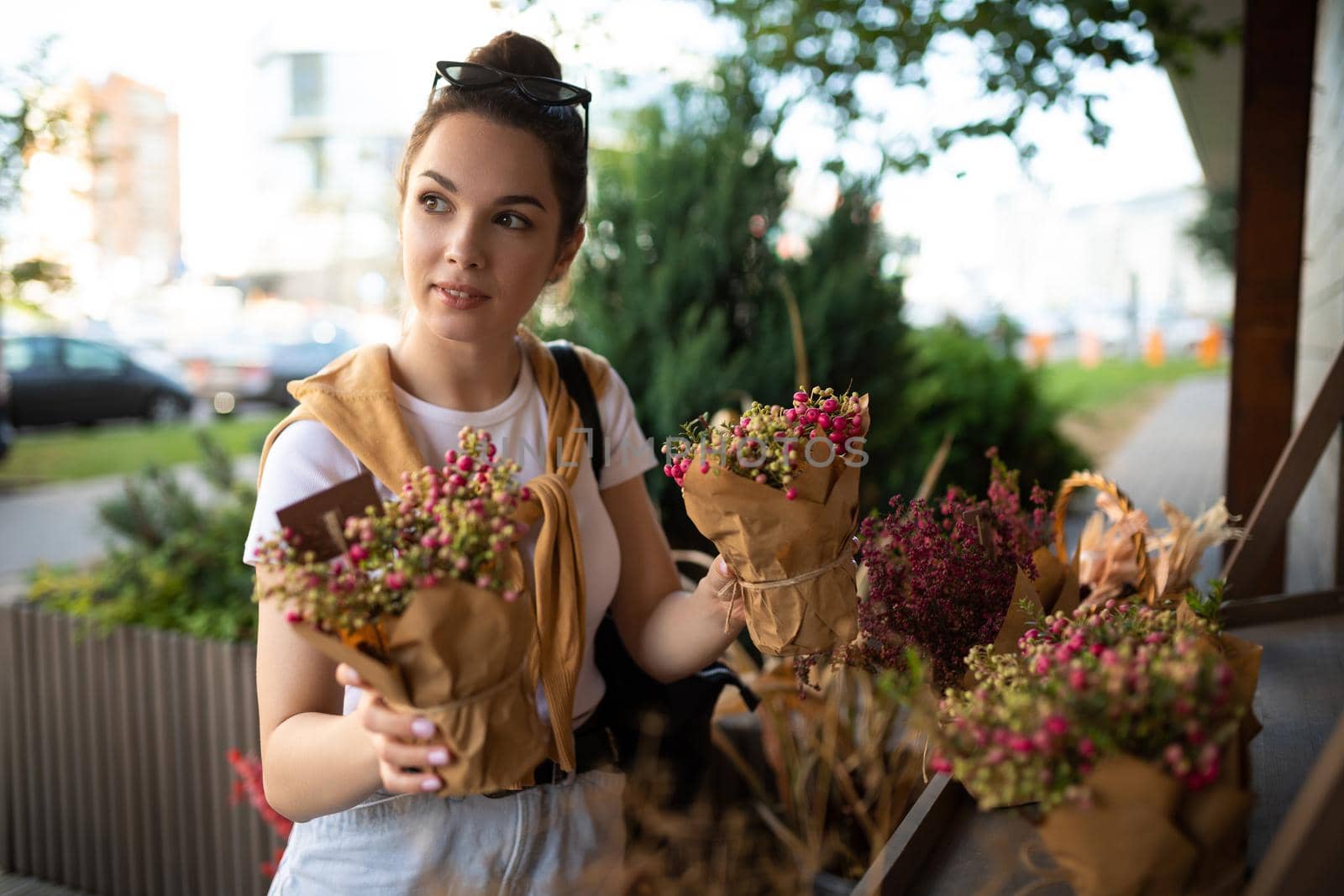 cute young woman holding her favorite flowers in a street garden shop.