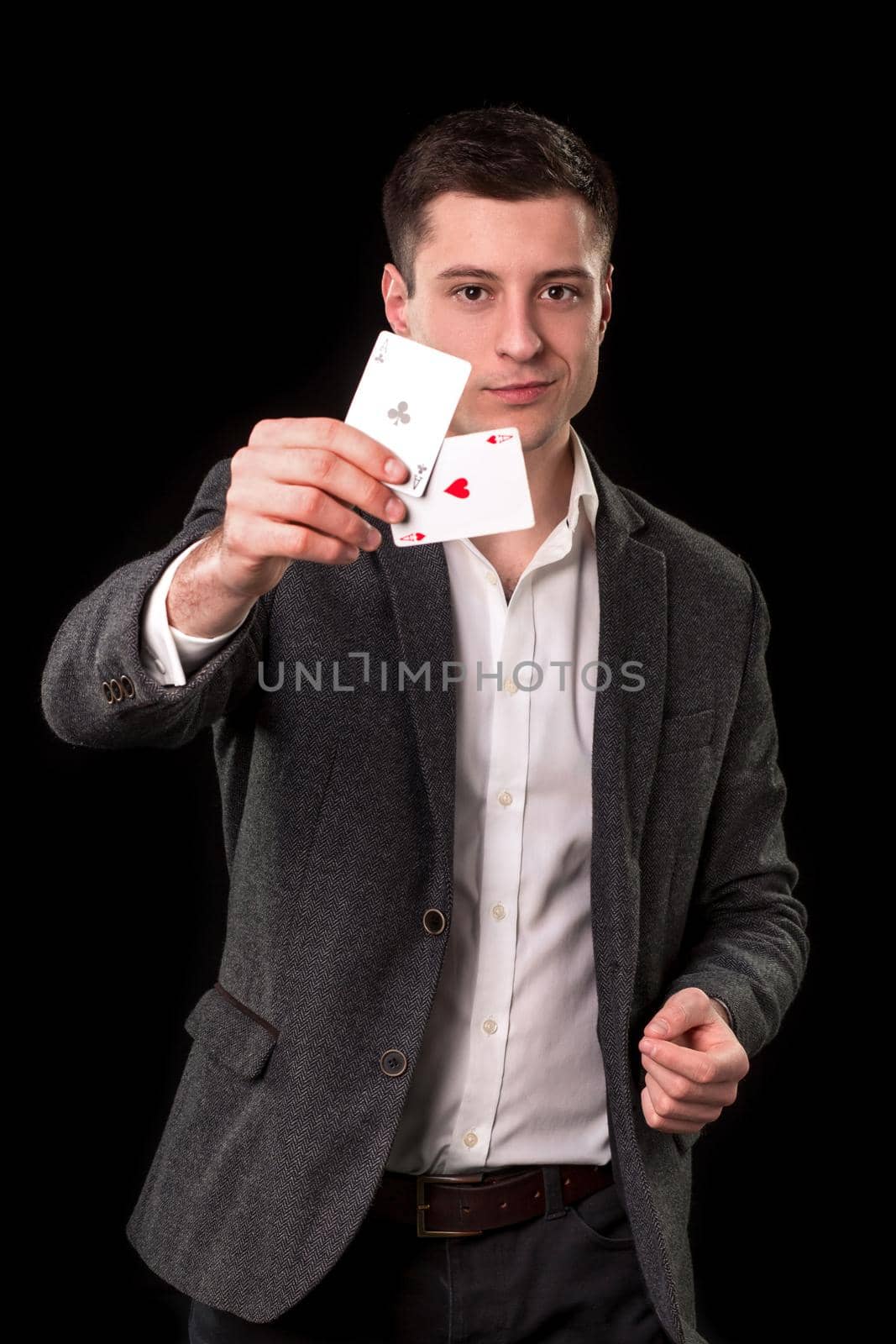 Young caucasian man wearing suit holding two aces in his hand on black background. Gambling concept. Casino by nazarovsergey