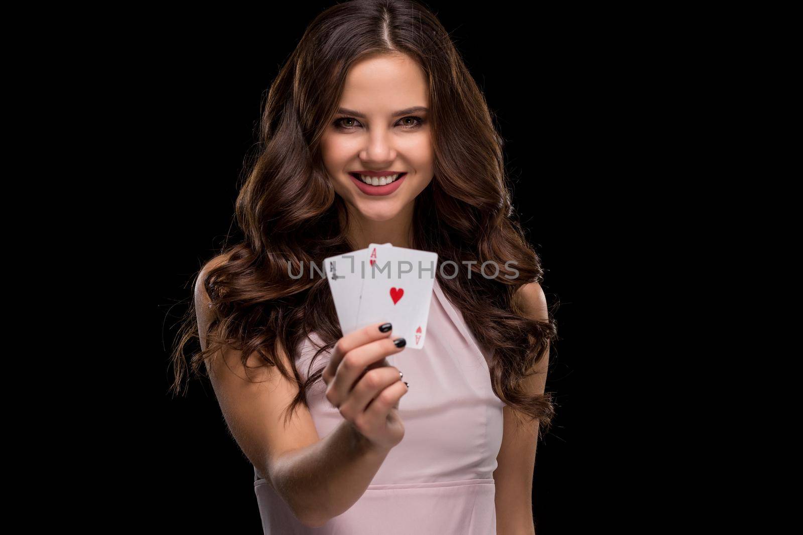 Attractive young woman in a sexy light dress holding the winning combination of poker cards. Two Aces. Studio shot on a black background. Casino