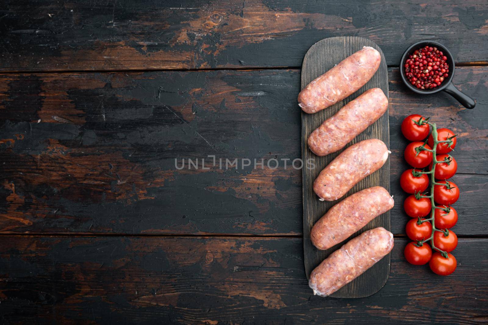 Traditional pork sausages, flat lay with space for text, on old dark wooden background.