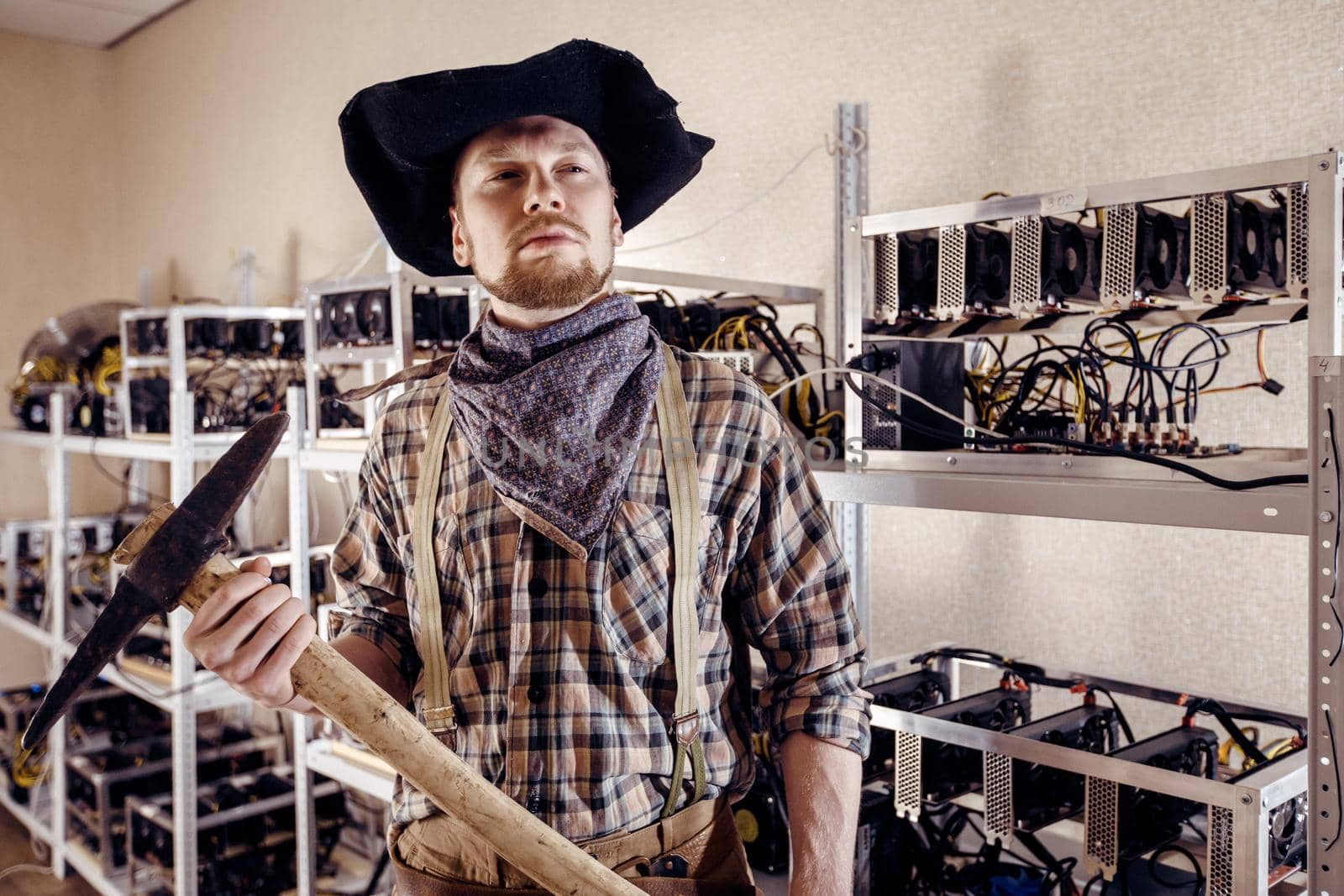 Man as a gold prospector with a tool on the background of computer devices
