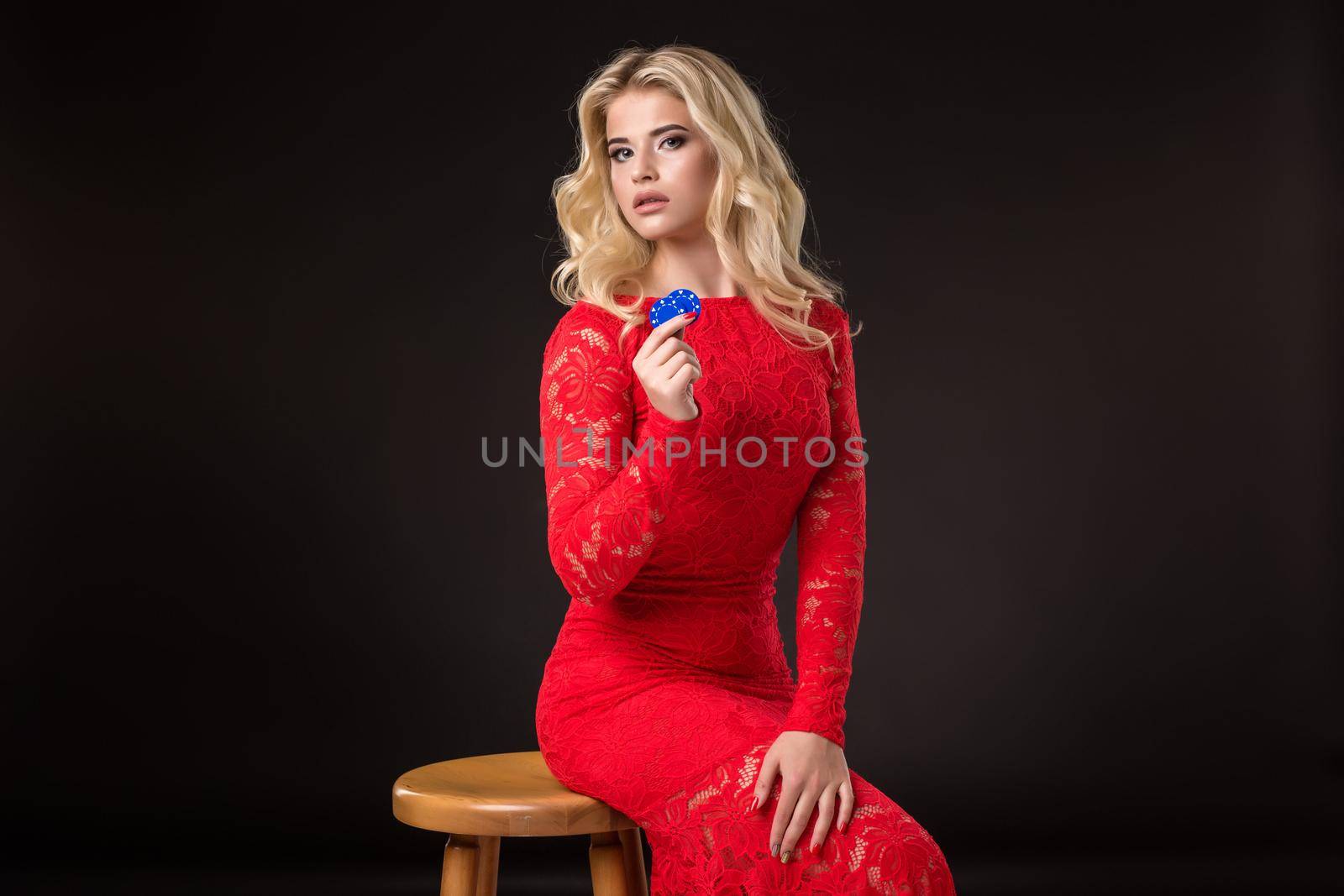 Young emotional woman holding a bunch of chips in her hands on a black background. Poker