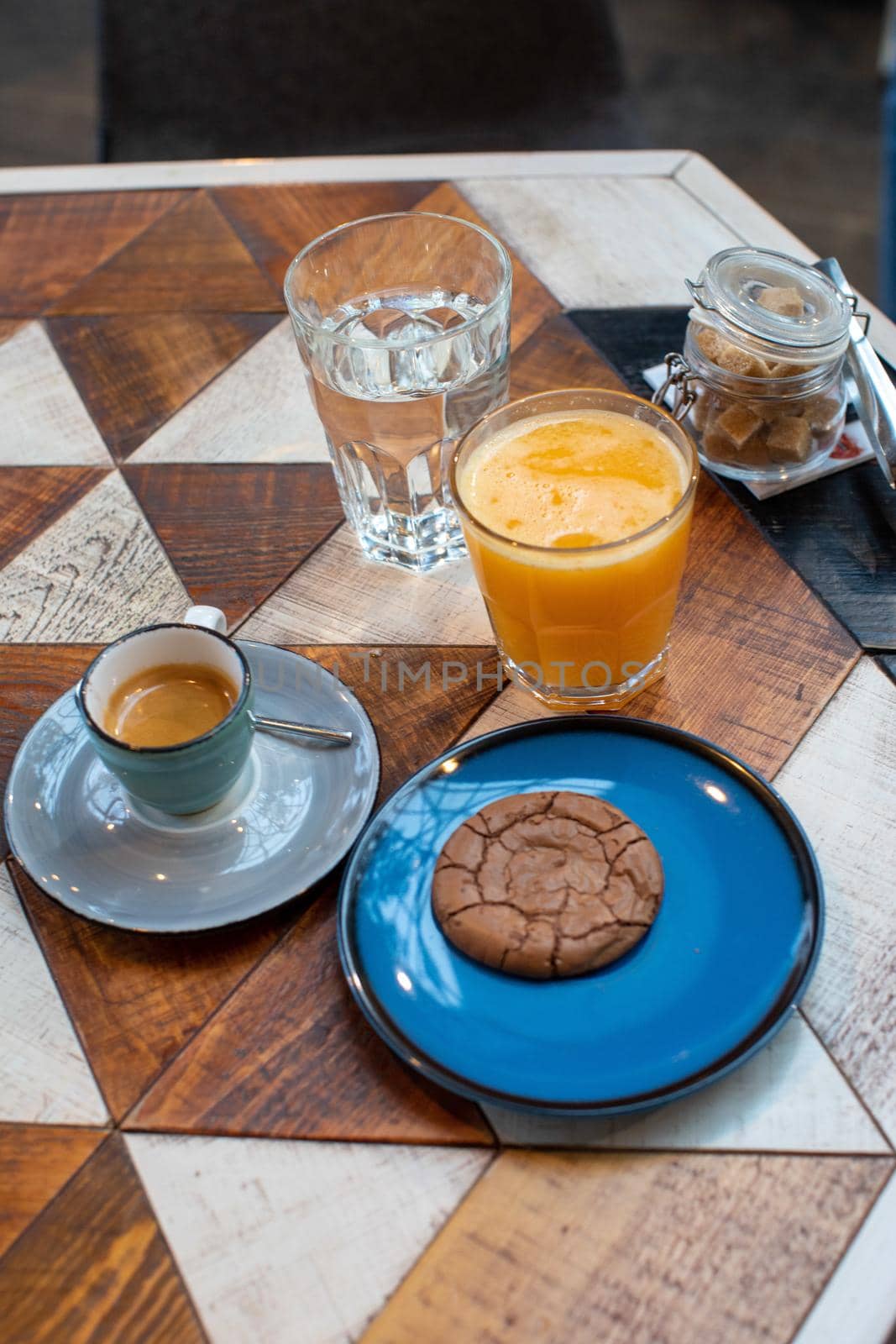 From above of table with cup of espresso cookie on plate and fresh orange juice