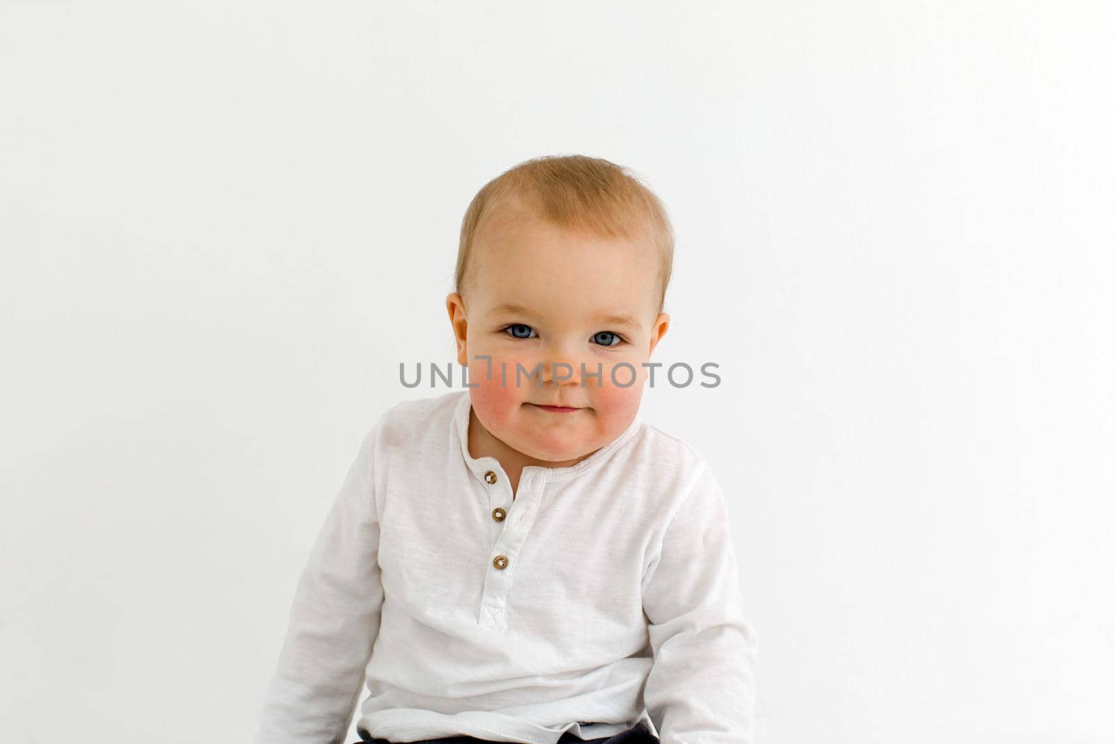Little vale toddler in white polo looking at camera isolated on white background