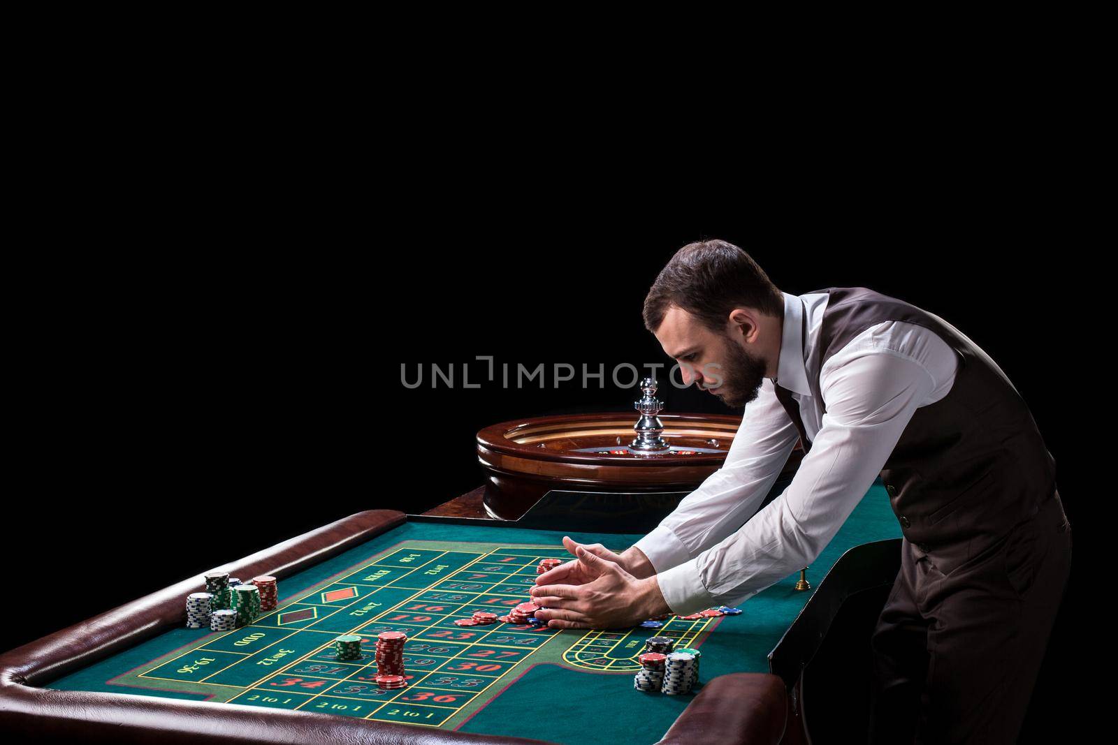 Croupier behind gambling table in a casino on a black background. Gambling. Casino. Roulette. Poker