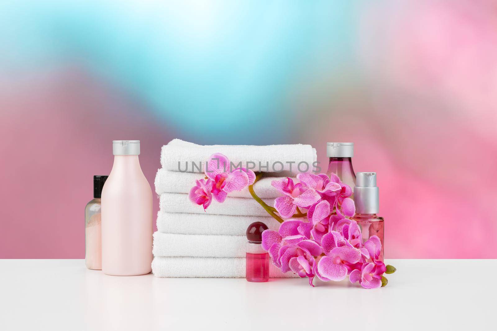 Towels with flowers on light table against blurred background, front view