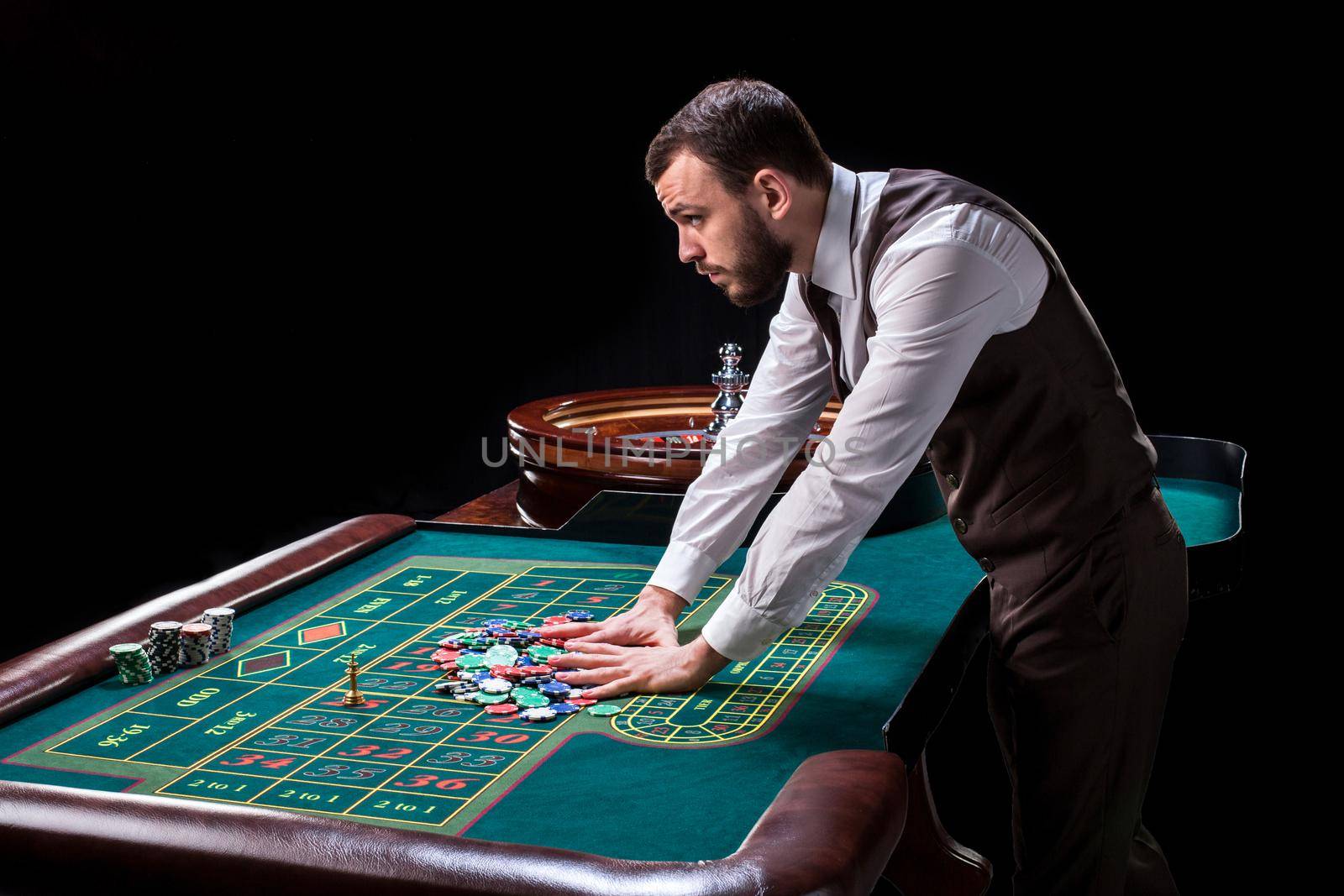 Croupier behind gambling table in a casino on a black background. Gambling. Casino. Roulette. Poker