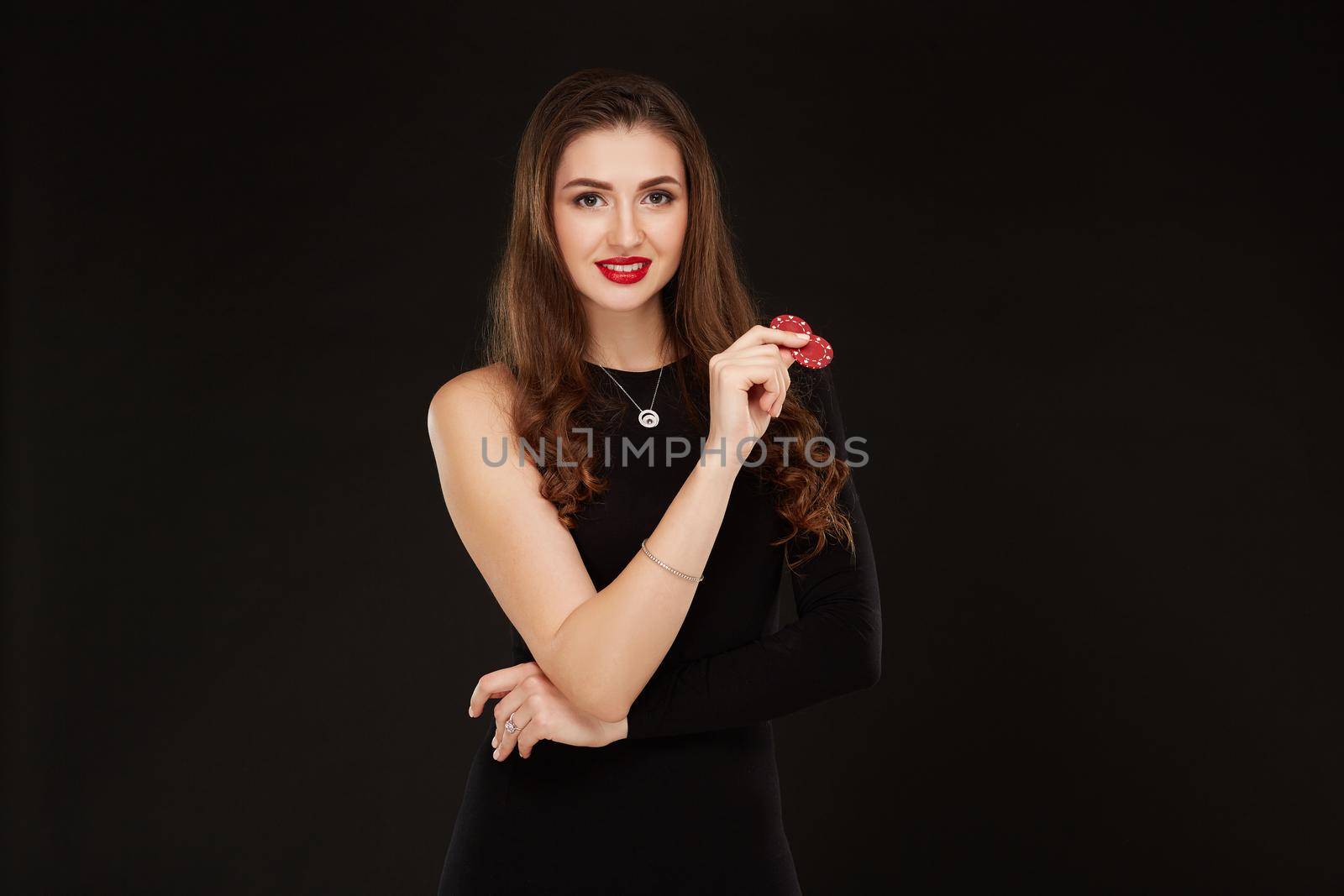 Sexy curly hair brunette posing with chips in her hands, poker concept black background by nazarovsergey