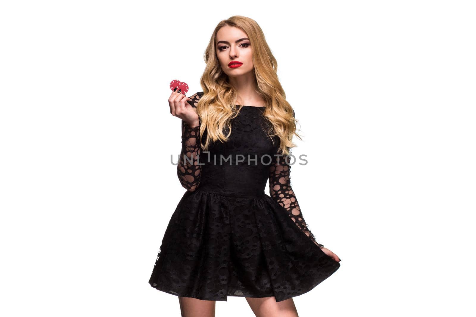 Beautiful blonde in a black dress with casino chips in hands isolated on a white background. Poker. Casino. Roulette Blackjack Spin. Caucasian young woman looking at the camera