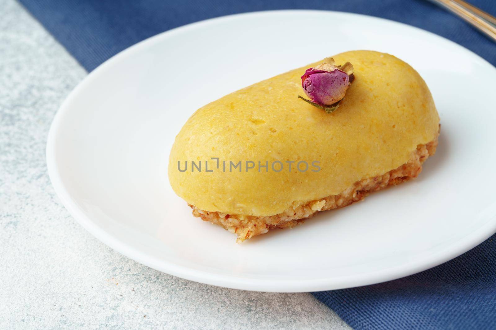 Mini mousse pastry dessert with rose on white plate, close up