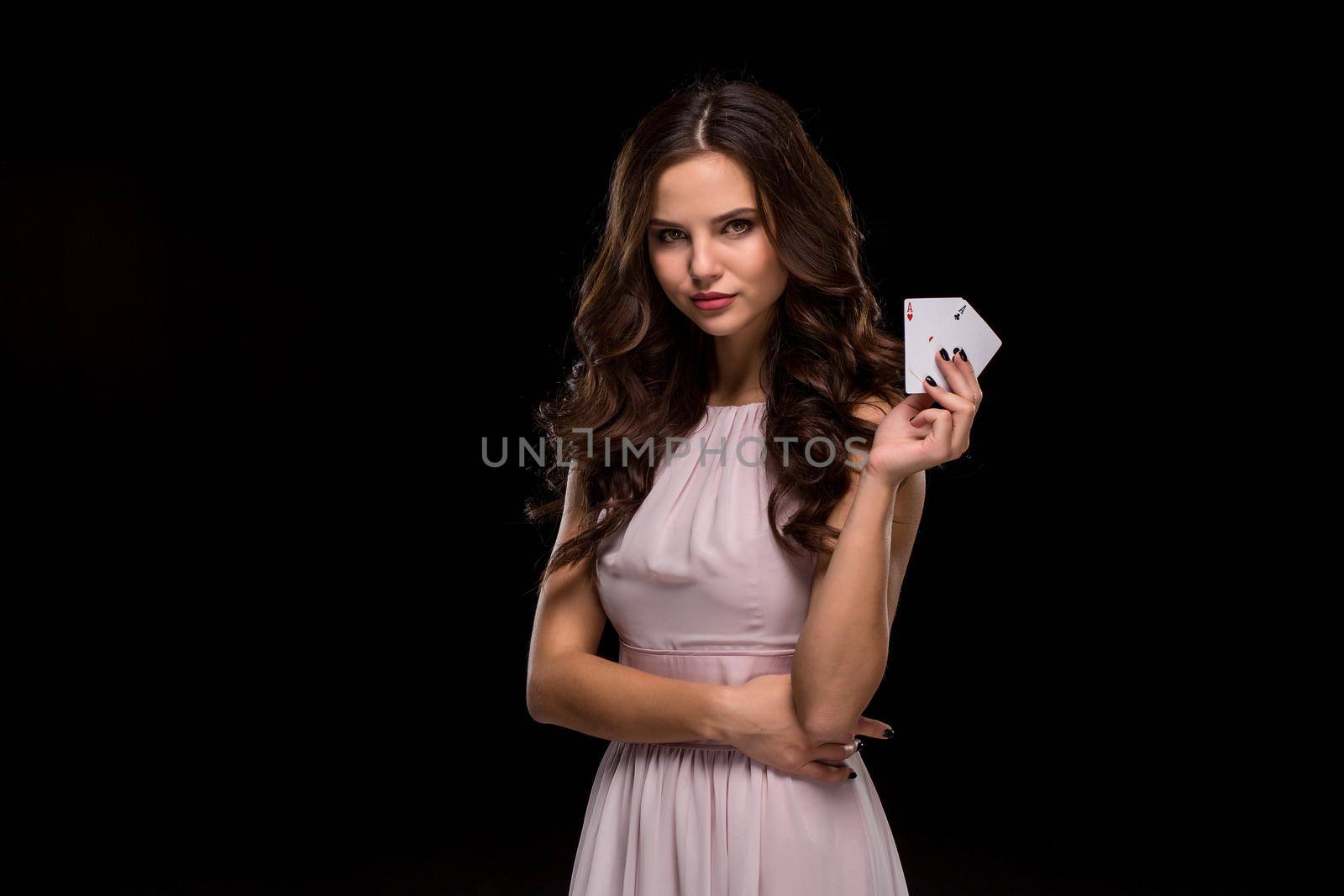Attractive young woman in a sexy light dress holding the winning combination of poker cards. Two Aces. Studio shot on a black background. Casino