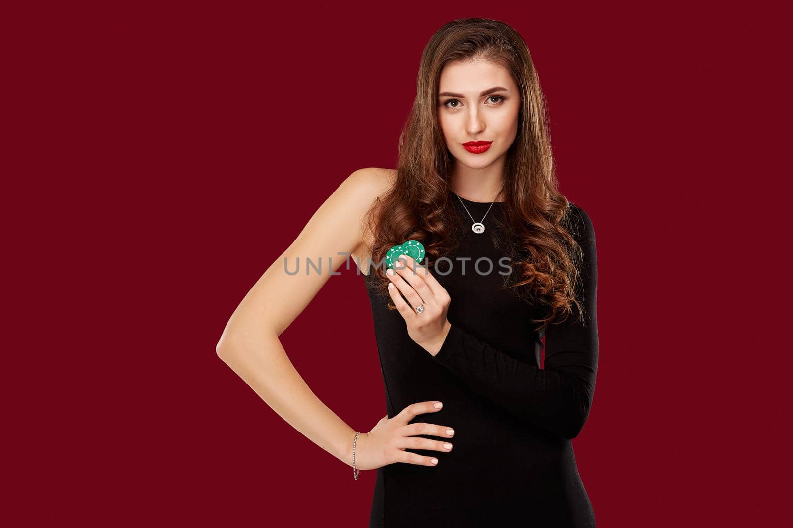 Pretty long hair woman in black dress holding chips for gambling by nazarovsergey