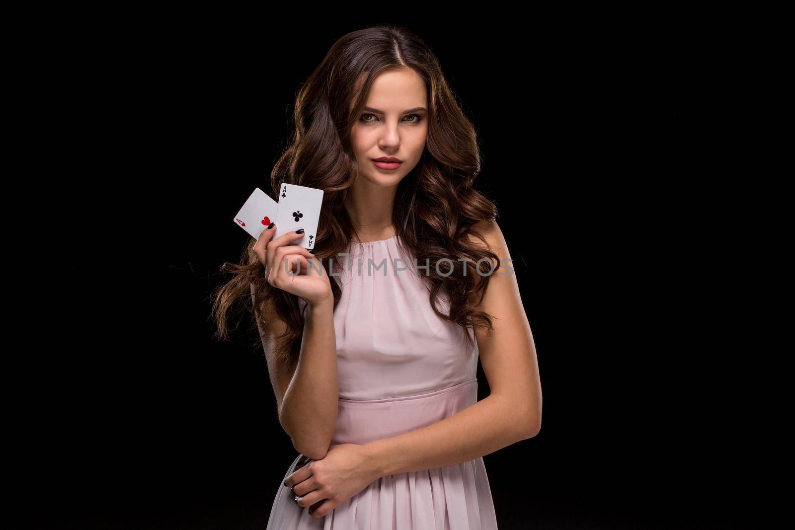 Attractive young woman in a sexy light dress holding the winning combination of poker cards. Two Aces. Studio shot on a black background. Casino