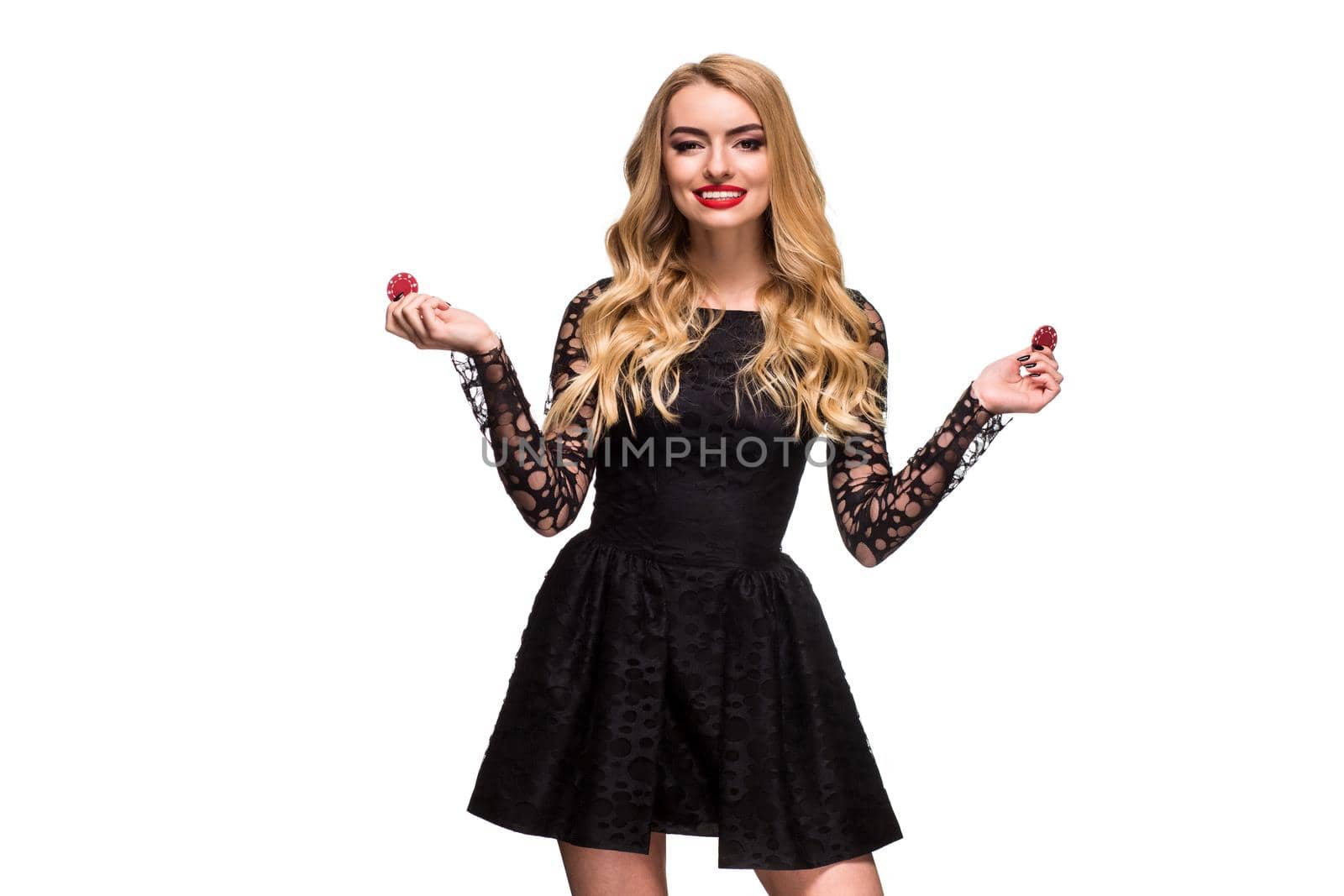 Beautiful blonde in a black dress with casino chips in hands isolated on a white background. Poker. Casino. Roulette Blackjack Spin. Caucasian young woman looking at the camera