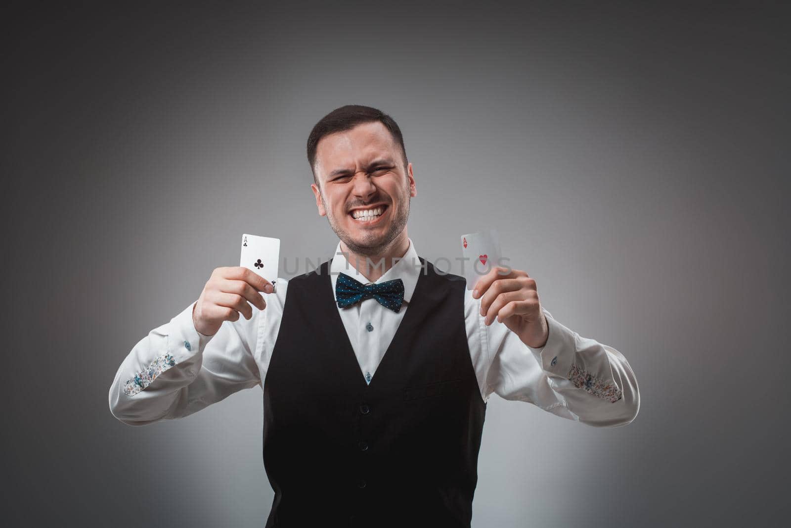 Young man in shirt and waistcoat shows his poker cards, studio shot by nazarovsergey