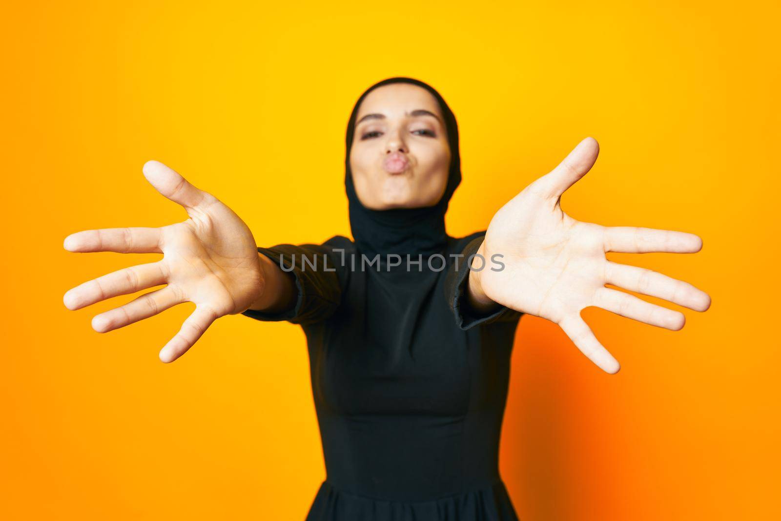 pretty woman in black hijab posing fashion hand gesture yellow background. High quality photo