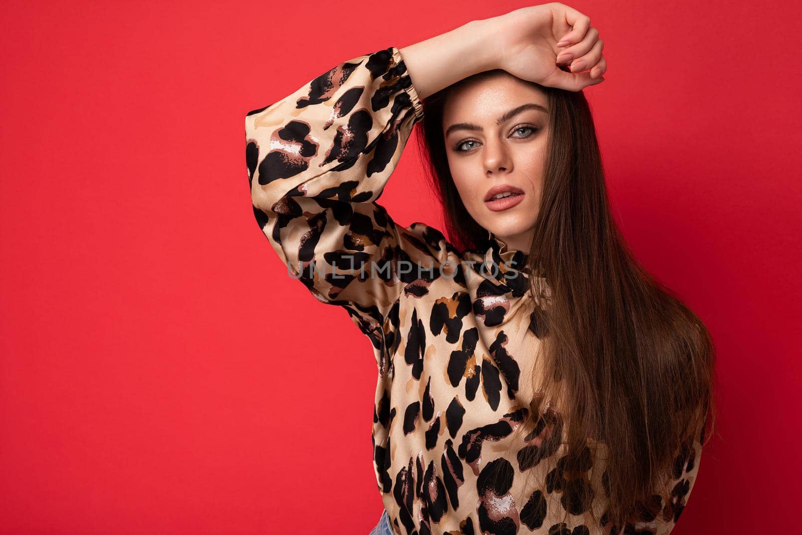 Fashion photo of young beautiful fashionable sexy brunette woman wearing stylish leopard blouse isolated on red background with empty space.