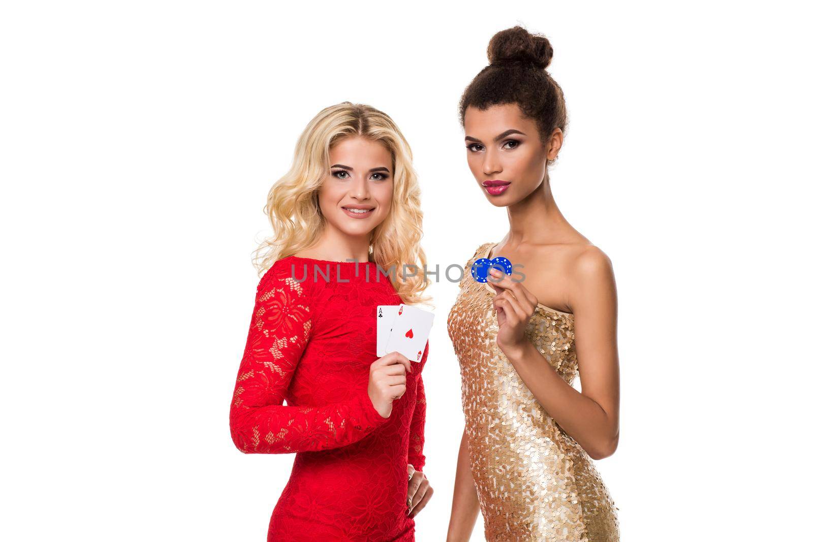 Beautiful african woman and Caucasian young woman with long light blonde hair in evening outfit. Holding playing cards and chips. Isolated on white background. Poker