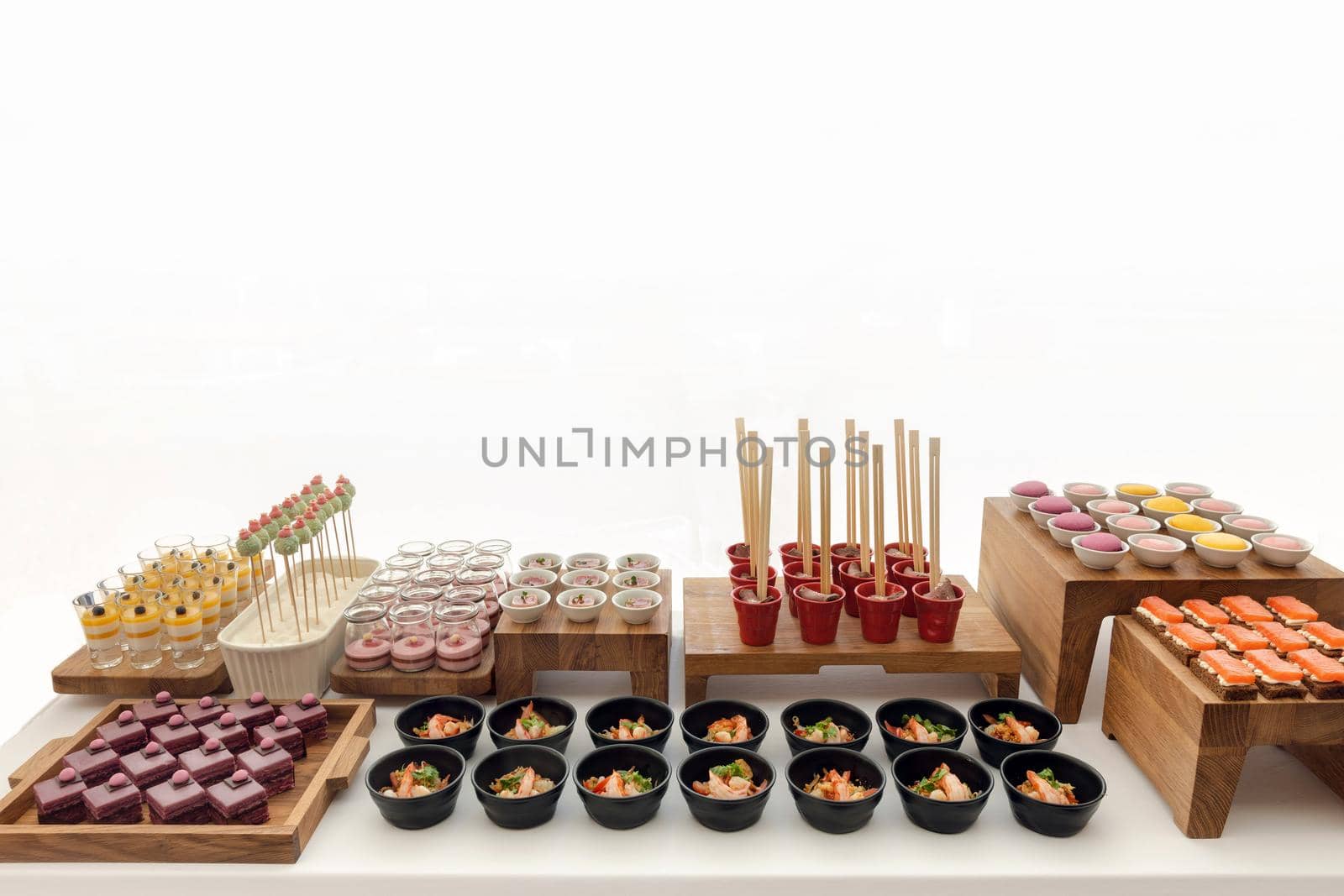 Assorted delicious sweets and pastry served on wooden trays at restaurant buffet isolated on white background