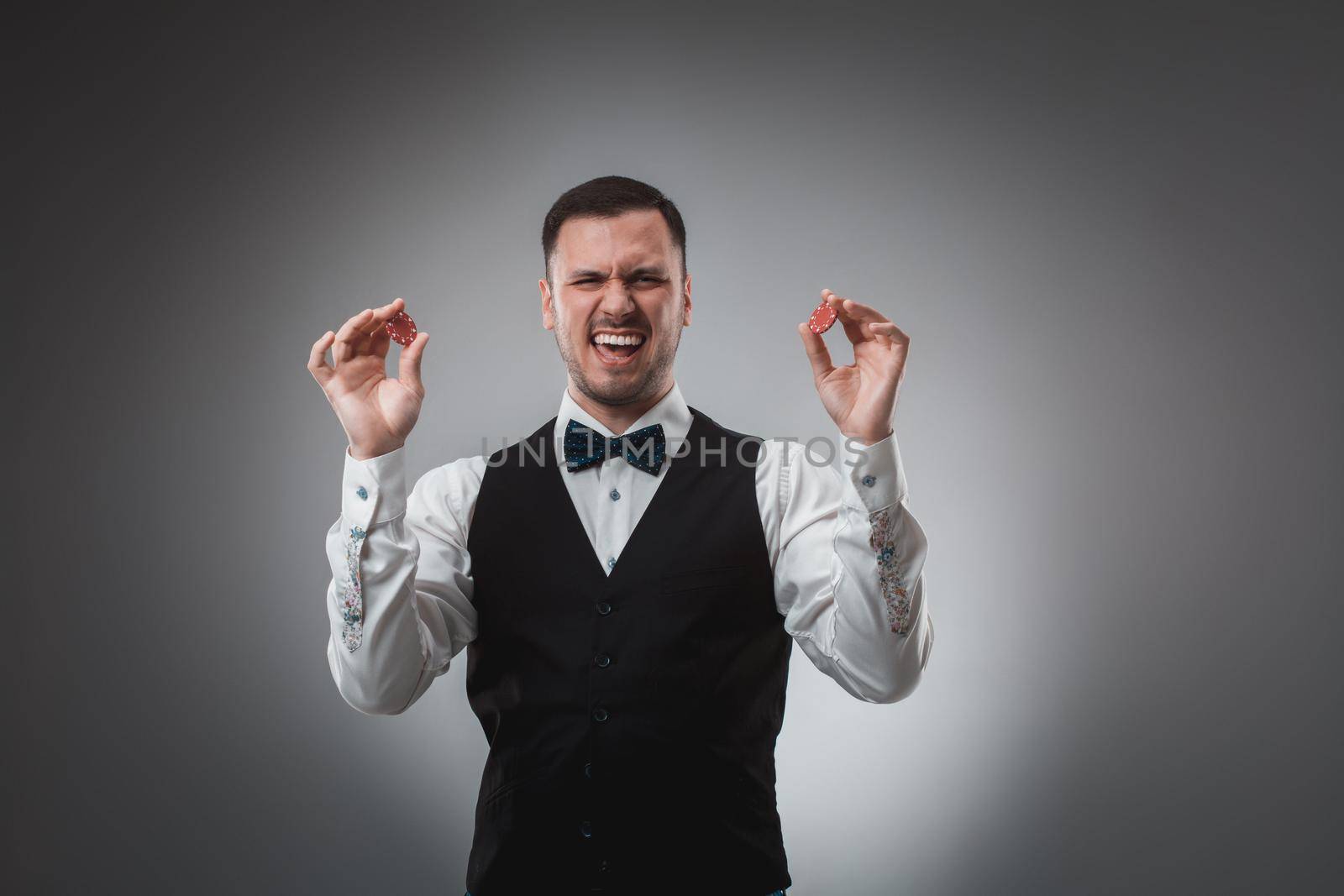 A man holding up red poker chips. Poker by nazarovsergey