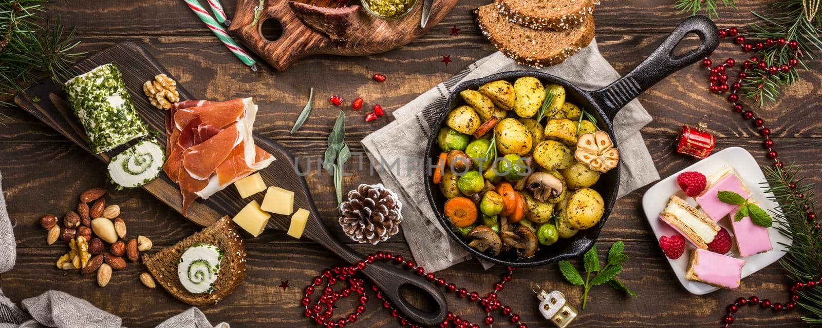 Banner of Delicious Christmas themed dinner table with roasted meat steak, appetizers and desserts. Top view. Holiday concept.