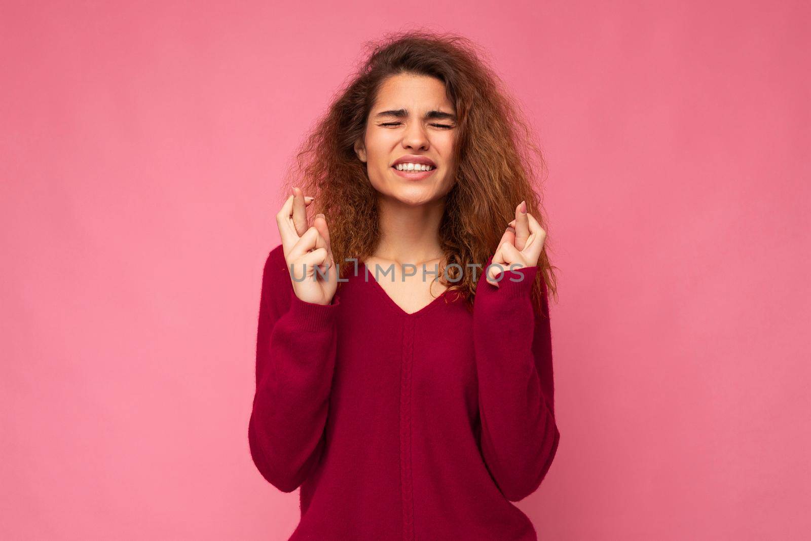 Photo of young emotional attractive woman with sincere emotions wearing trendy clothes isolated over background with empty space and gesturing fingers crossed with hope. Gesture concept by TRMK
