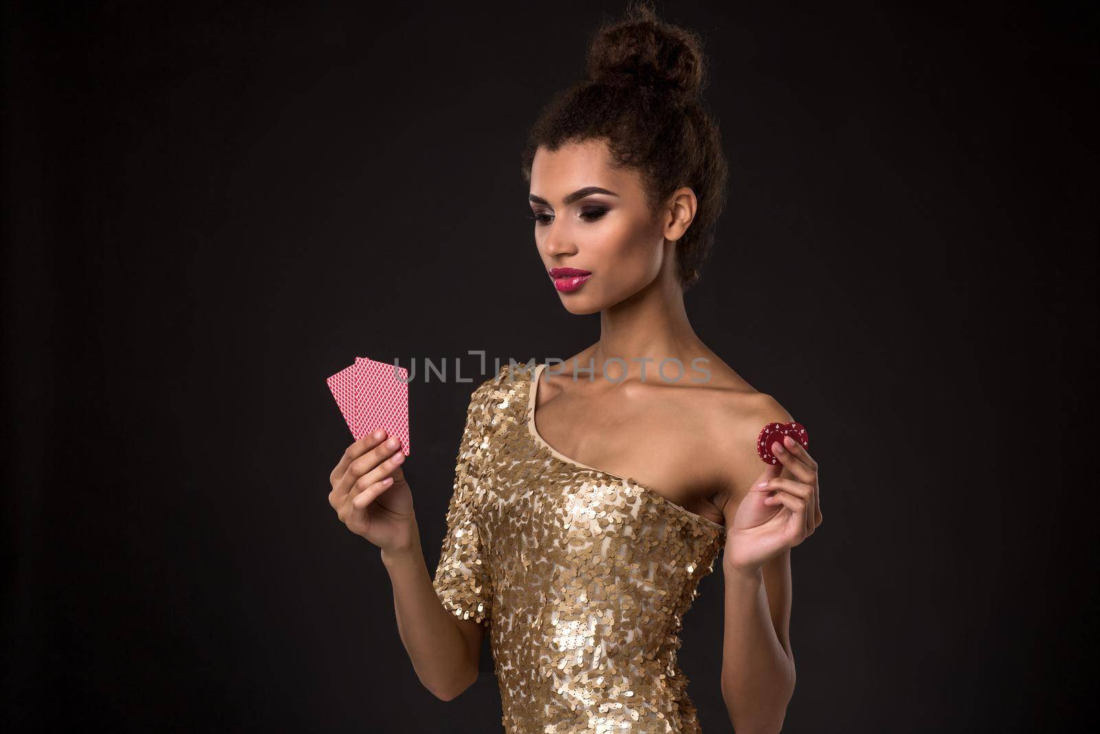 Woman winning - Young woman in a classy gold dress holding two cards and two red chips, a poker of aces card combination. by nazarovsergey