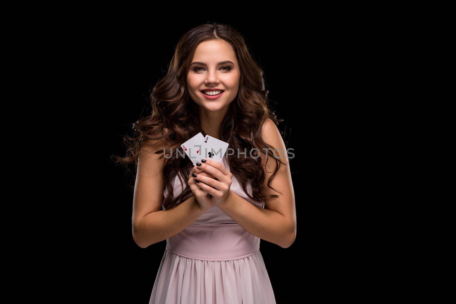 Attractive young woman in a sexy light dress holding the winning combination of poker cards. Two Aces. Studio shot on a black background. Casino