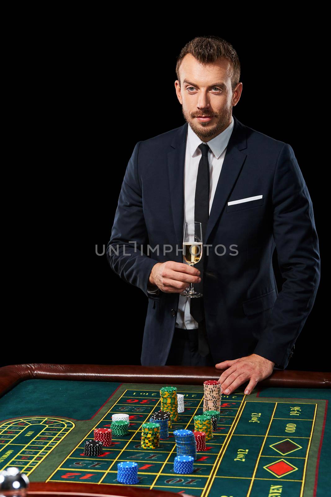 man in a suit playing roulette. addiction to gambling. In the hands of a glass