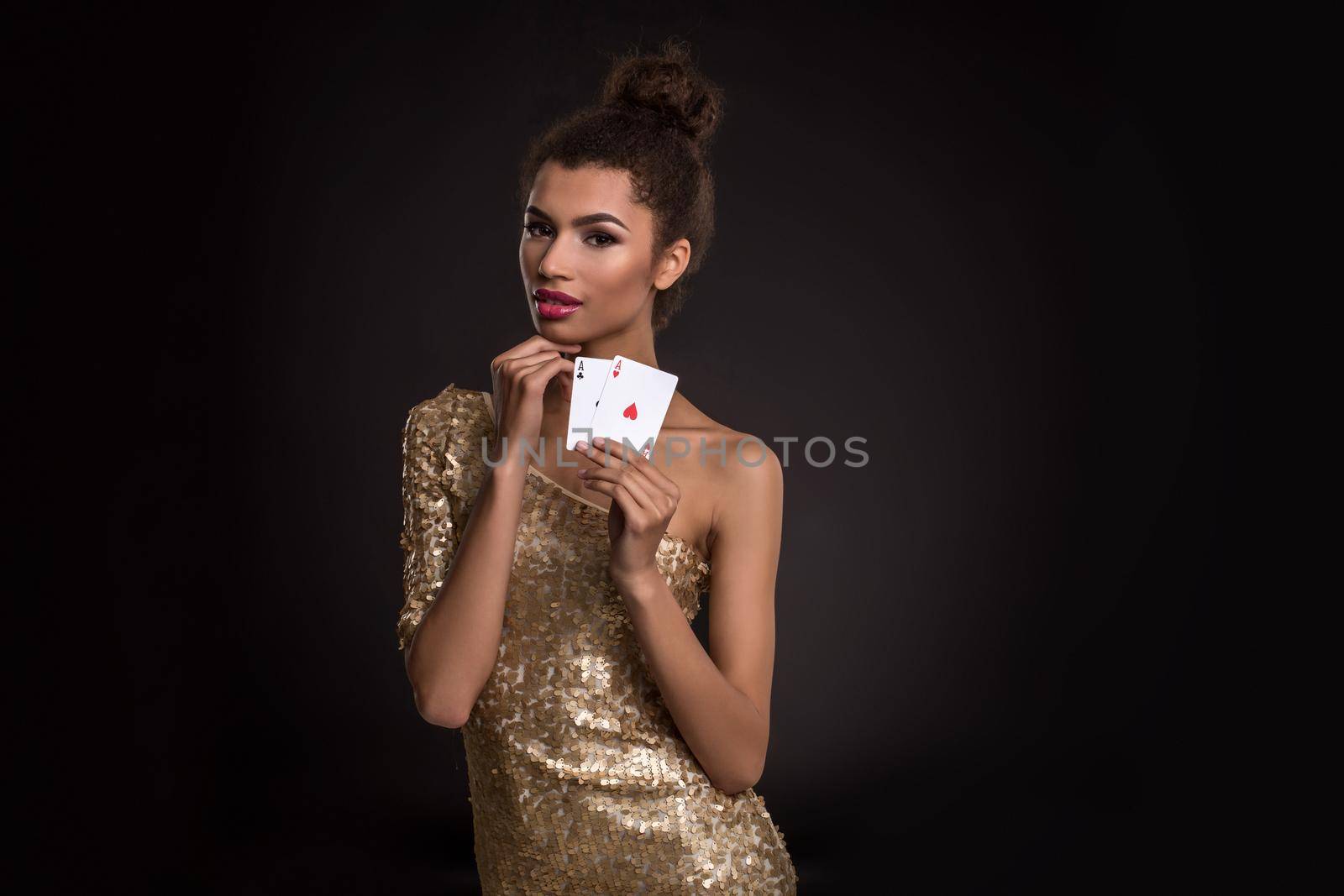 Pretty african girl shows two aces in casino poker and win Young woman in studio on black background