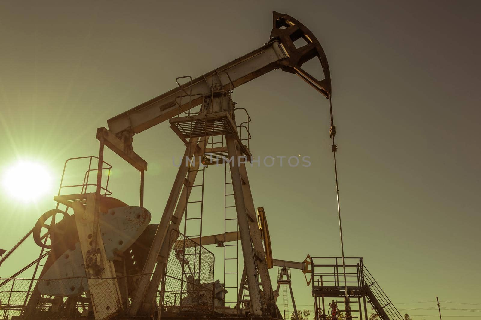 Oil pump rig operation on the platform in oil and gas industry. Pumpjack, industrial equipment. Oilfield site, oil pump are running. Rocking machines for power genertion. Petroleum concept. Toned.