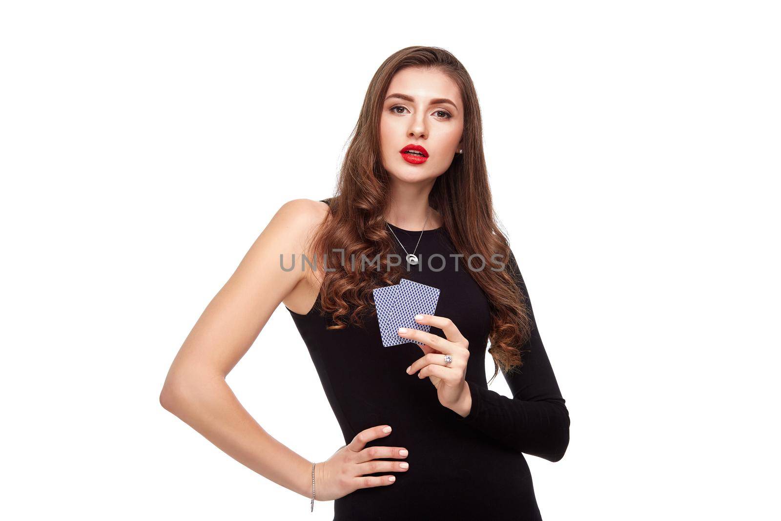 Beautiful confident woman in a sexy black dress showing poker cards, looking at camera with copy place. Studio shot on white background. Casino