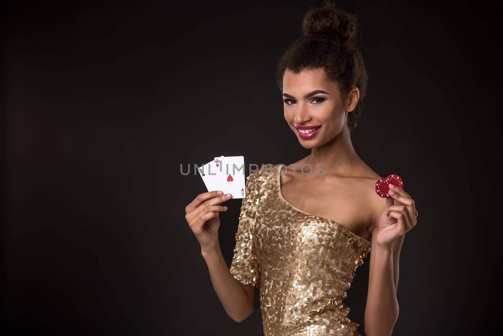 Woman winning - Young woman in a classy gold dress holding two aces and two red chips, a poker of aces card combination. by nazarovsergey