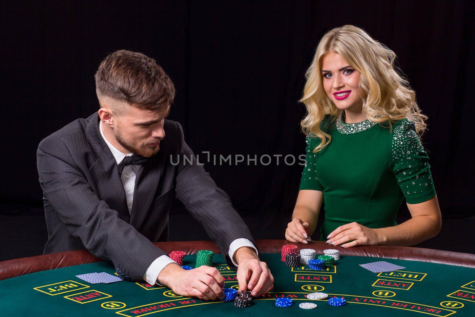 couple playing poker at the table. The blonde girl and a guy in a suit.