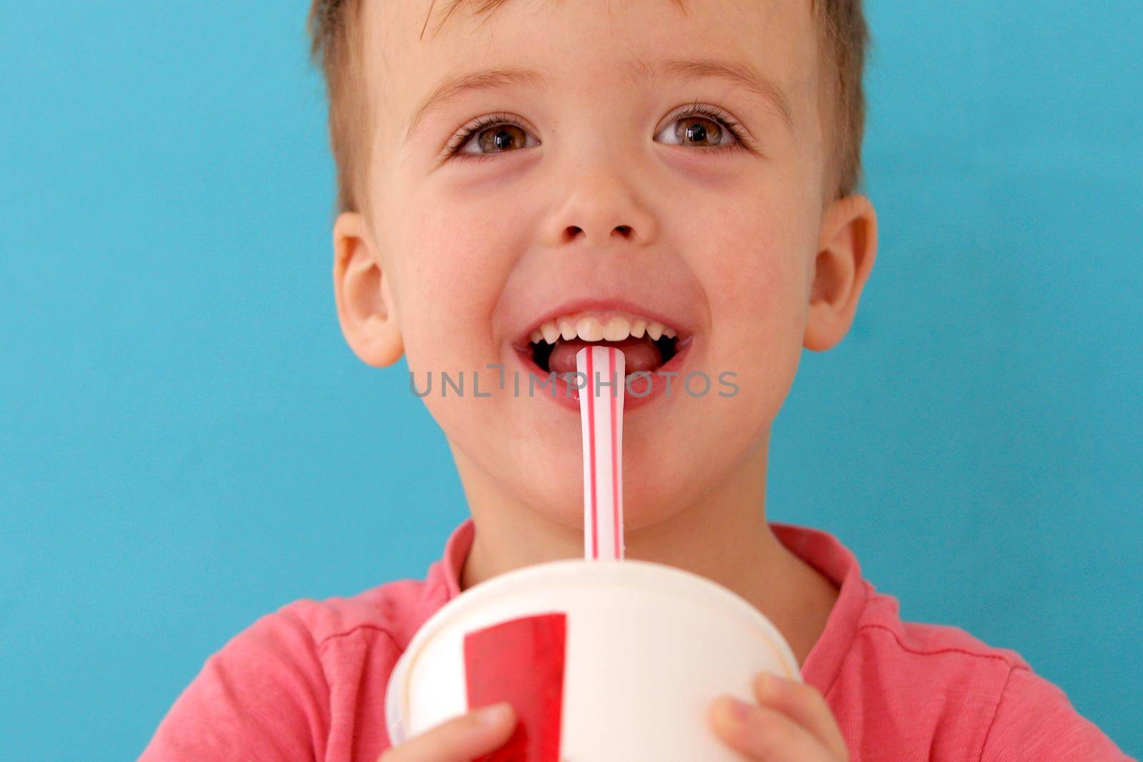 Cute little baby boy drinking milkshake blue background