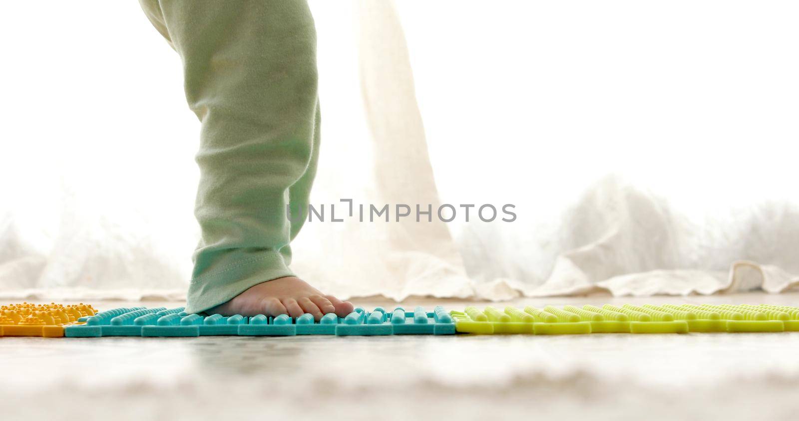 Child on massage mat doing exercises for flatfoot prevention by Demkat