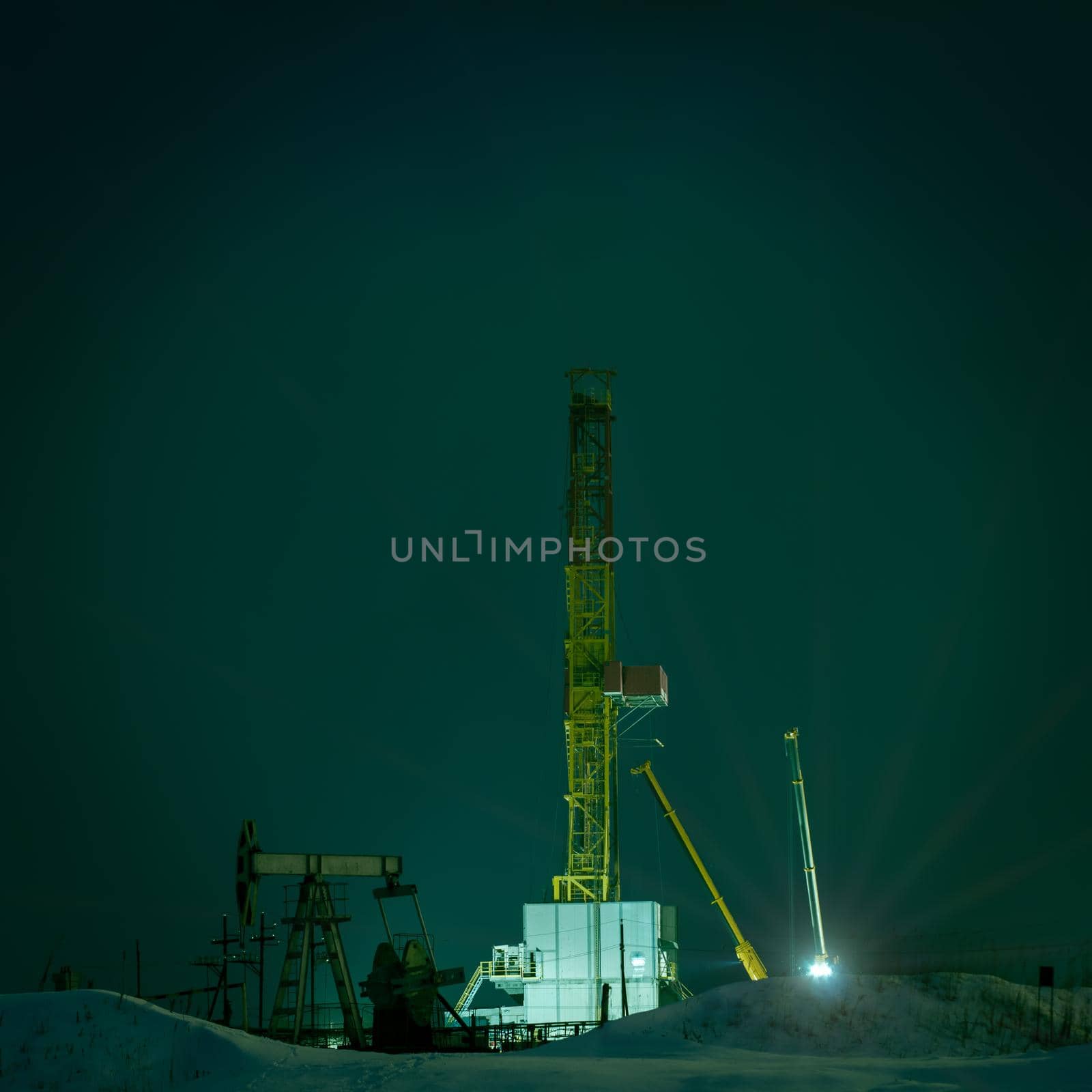 Night view of a derrick drilling and oil pump jack. Drilling rig at night.