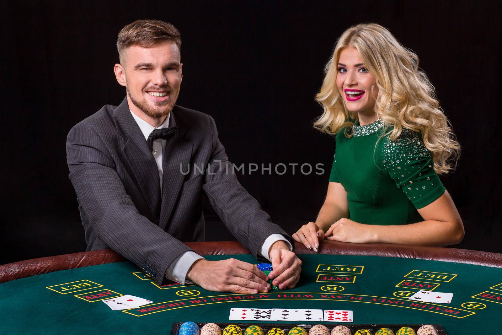 couple playing poker at the green table. The blonde girl and a guy in a suit. happy win