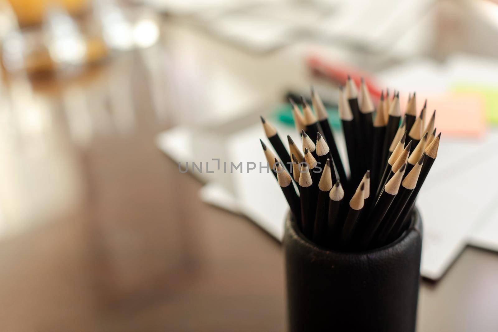 From above bunch of graphite pencil in holder on table with blurred stationery items