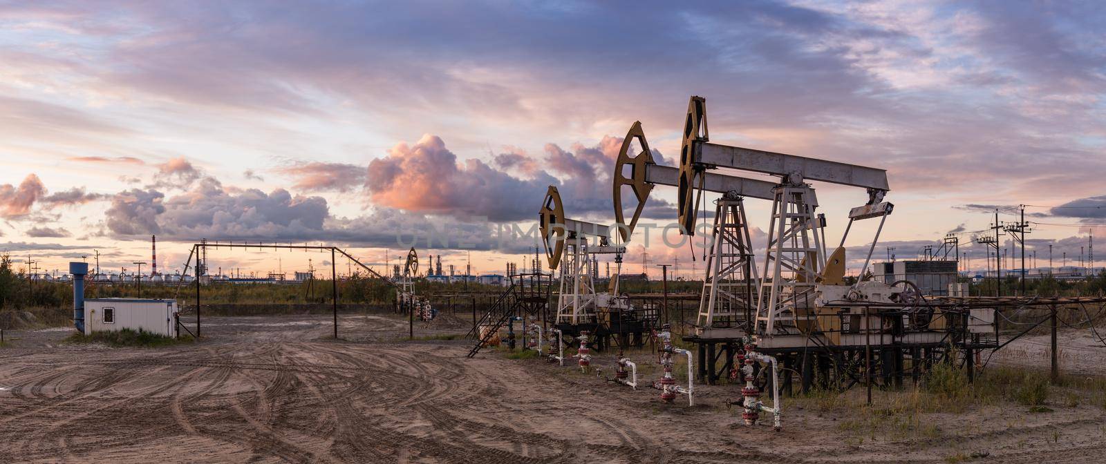 Rocking machines for power genertion. Petroleum concept. Oil and gas industry. Panoramic of a pumpjack and oil refinery. by bashta