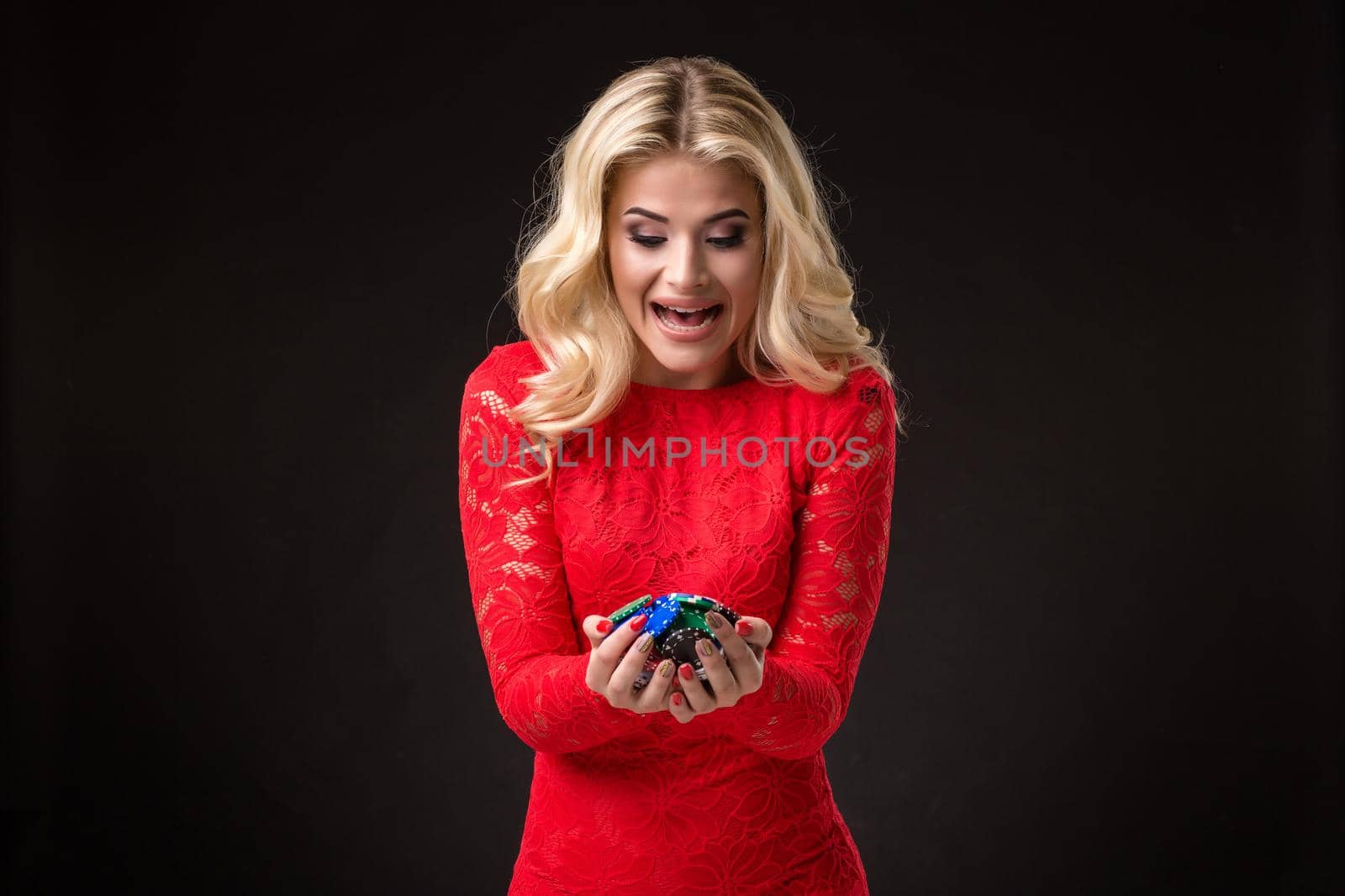 Young beautiful emotional woman with chips in hands on a black background in the studio. Poker by nazarovsergey
