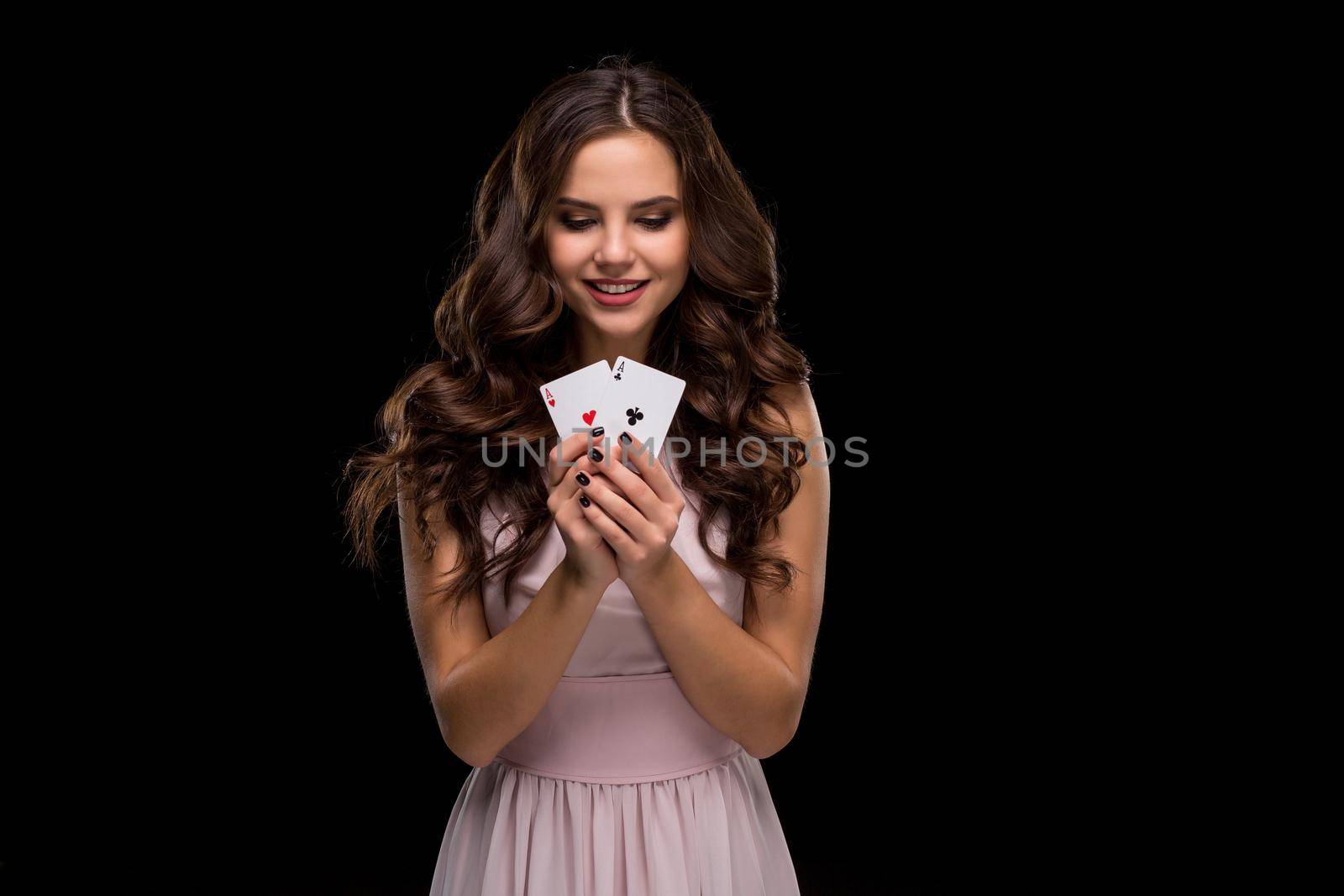 Attractive young woman in a sexy light dress holding the winning combination of poker cards. Two Aces. Studio shot on a black background. Casino