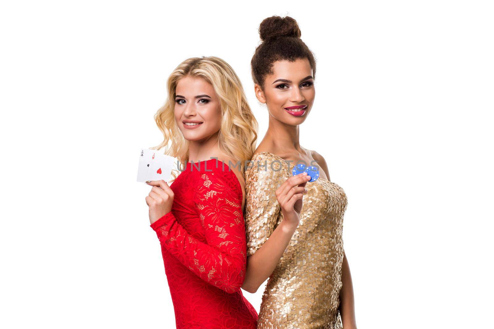 Beautiful african woman and Caucasian young woman with long light blonde hair in evening outfit. Holding playing cards and chips. Isolated on white background. Poker