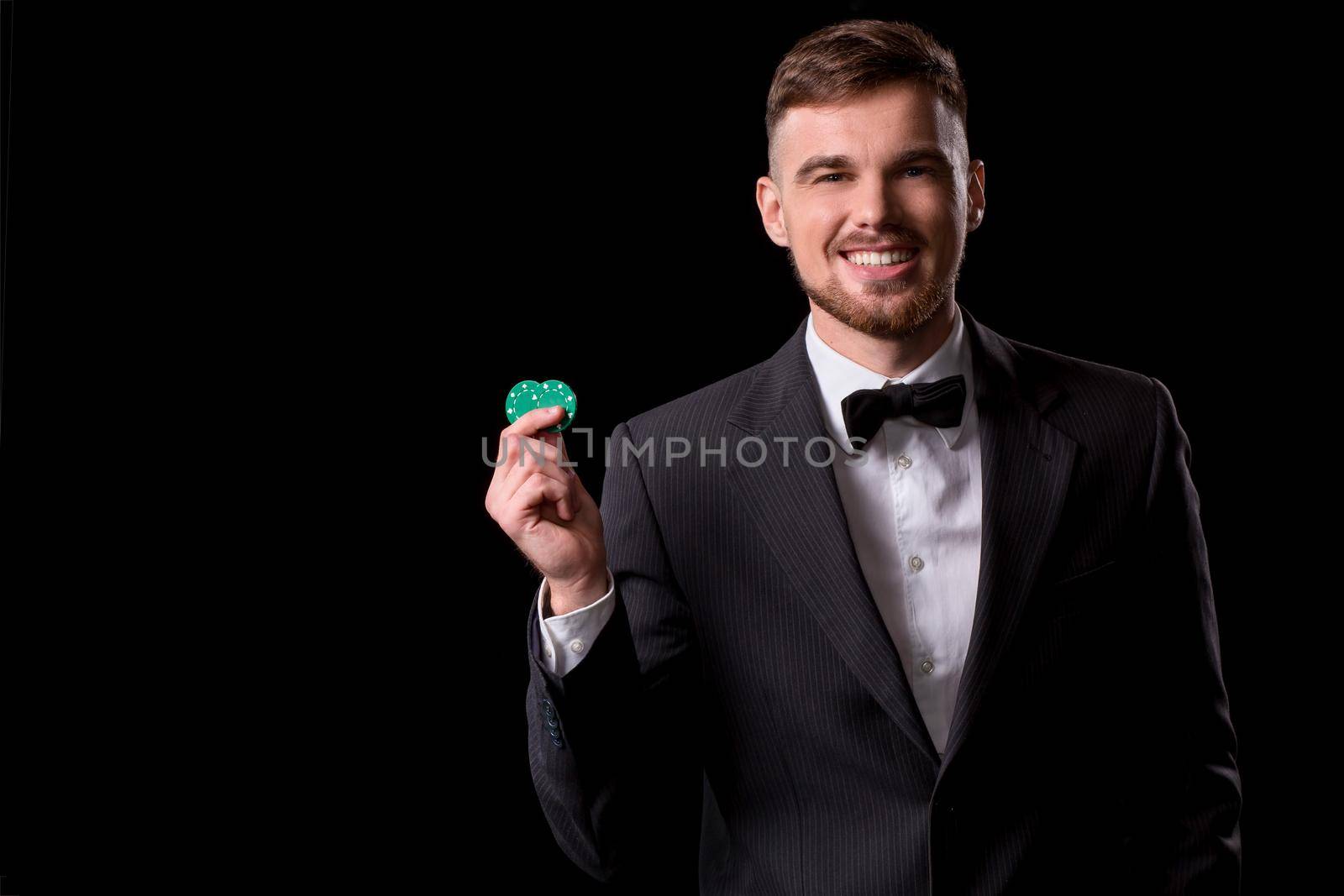 man in a suit posing with chips for gambling on black background